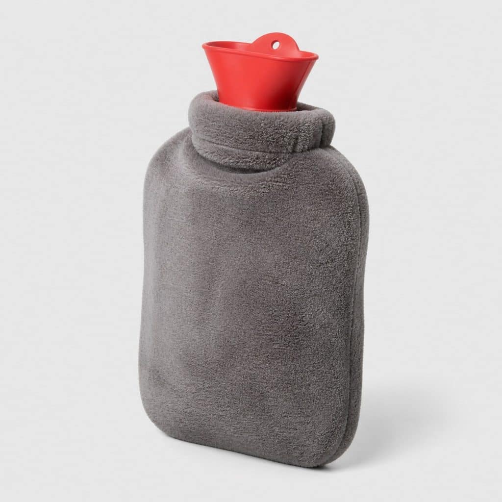 Bouillotte à eau avec housse polaire posée seule sur fond neutre