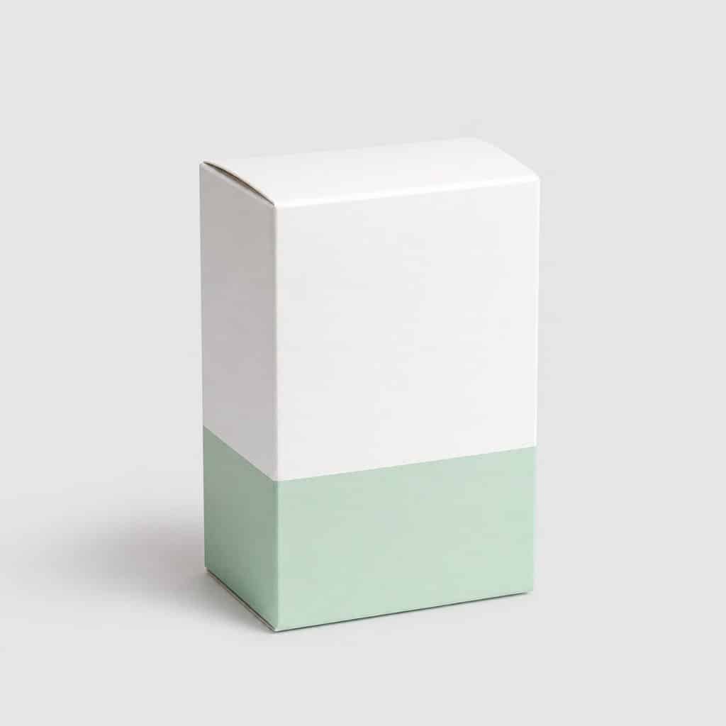 Boîte de gélules blanche et verte pâle posée seule sur fond neutre