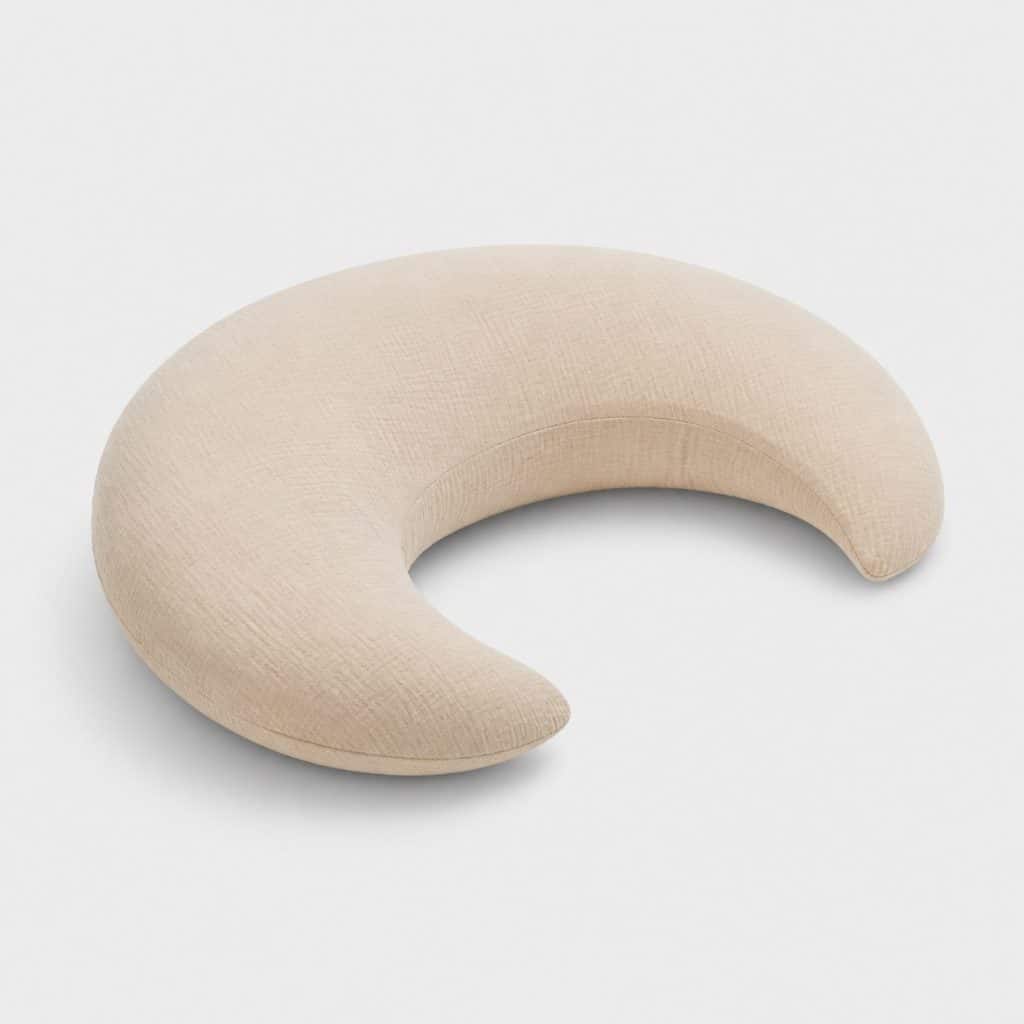 Coussin d'allaitement en forme de croissant beige sur fond clair