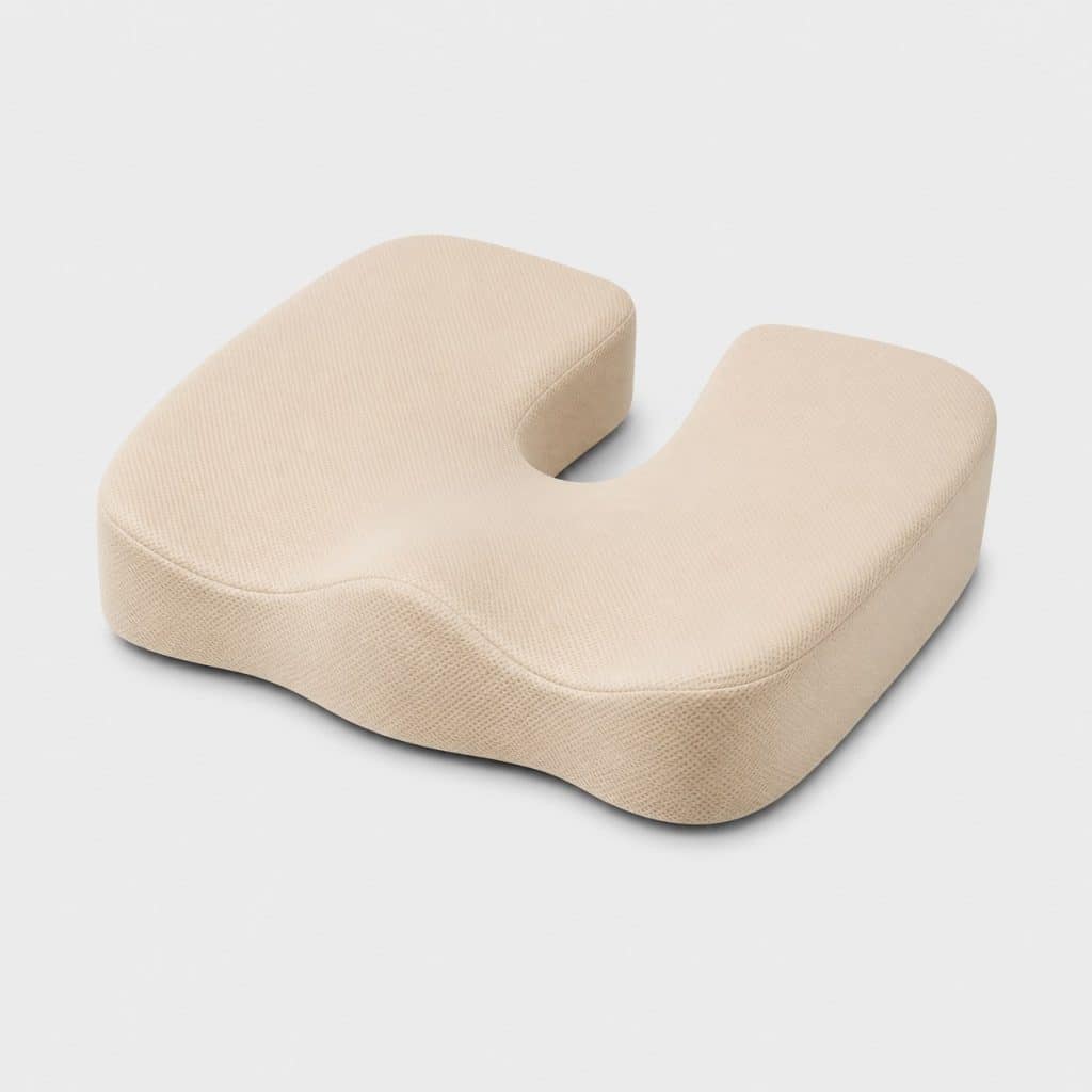 Coussin en mousse beige avec découpe centrale ergonomique posé seul sur fond neutre