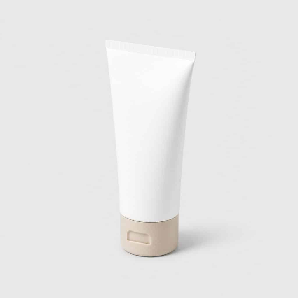 Tube de crème blanc et beige posé seul sur fond neutre clair