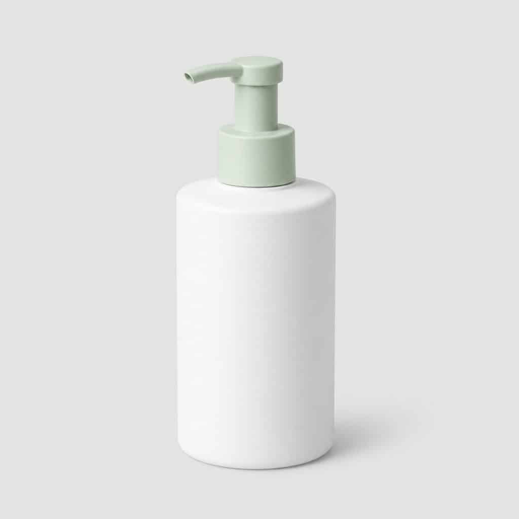 Flacon pompe blanc et vert pâle de gel posé seul sur fond neutre