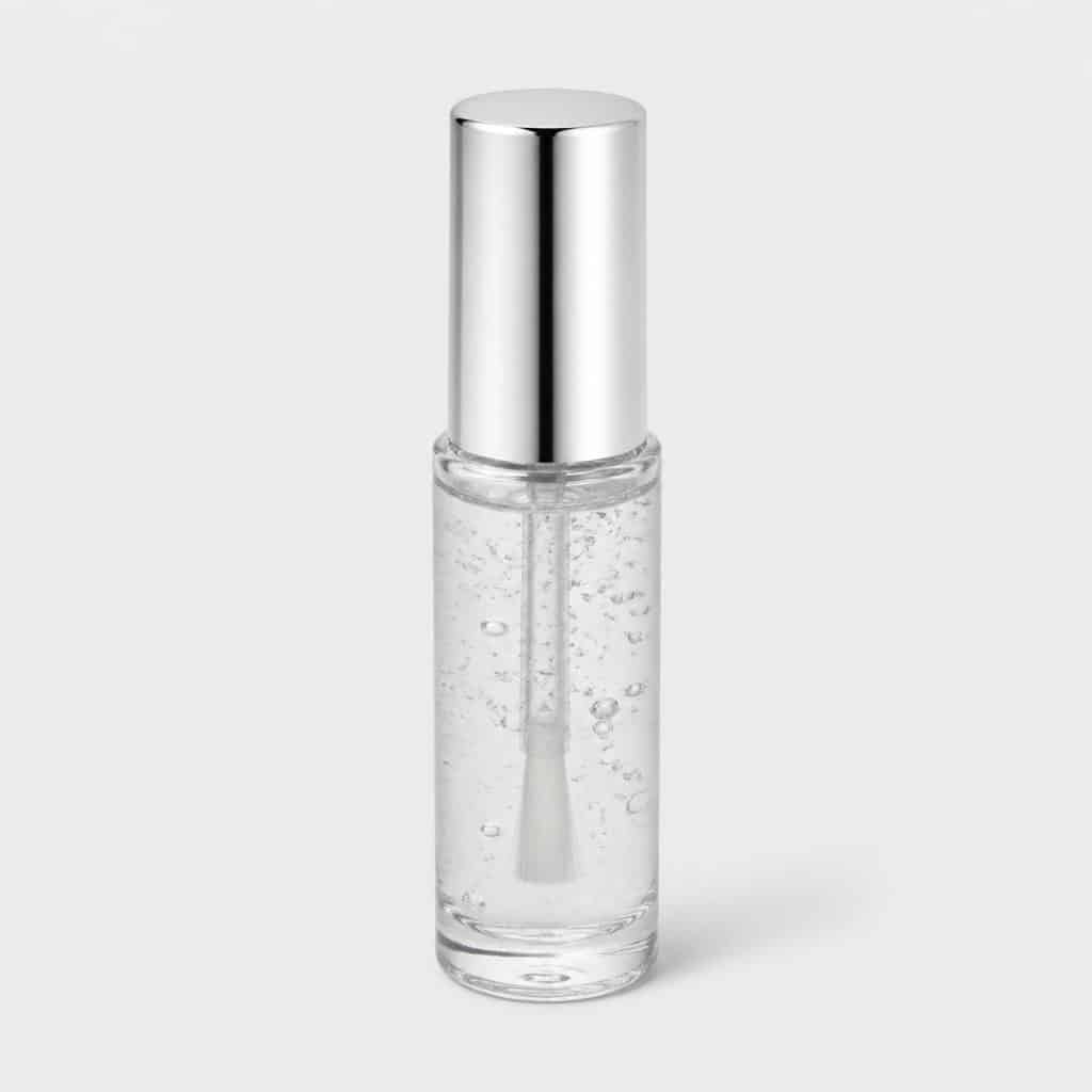 Flacon transparent de sérum avec pinceau applicateur posé seul sur fond neutre clair