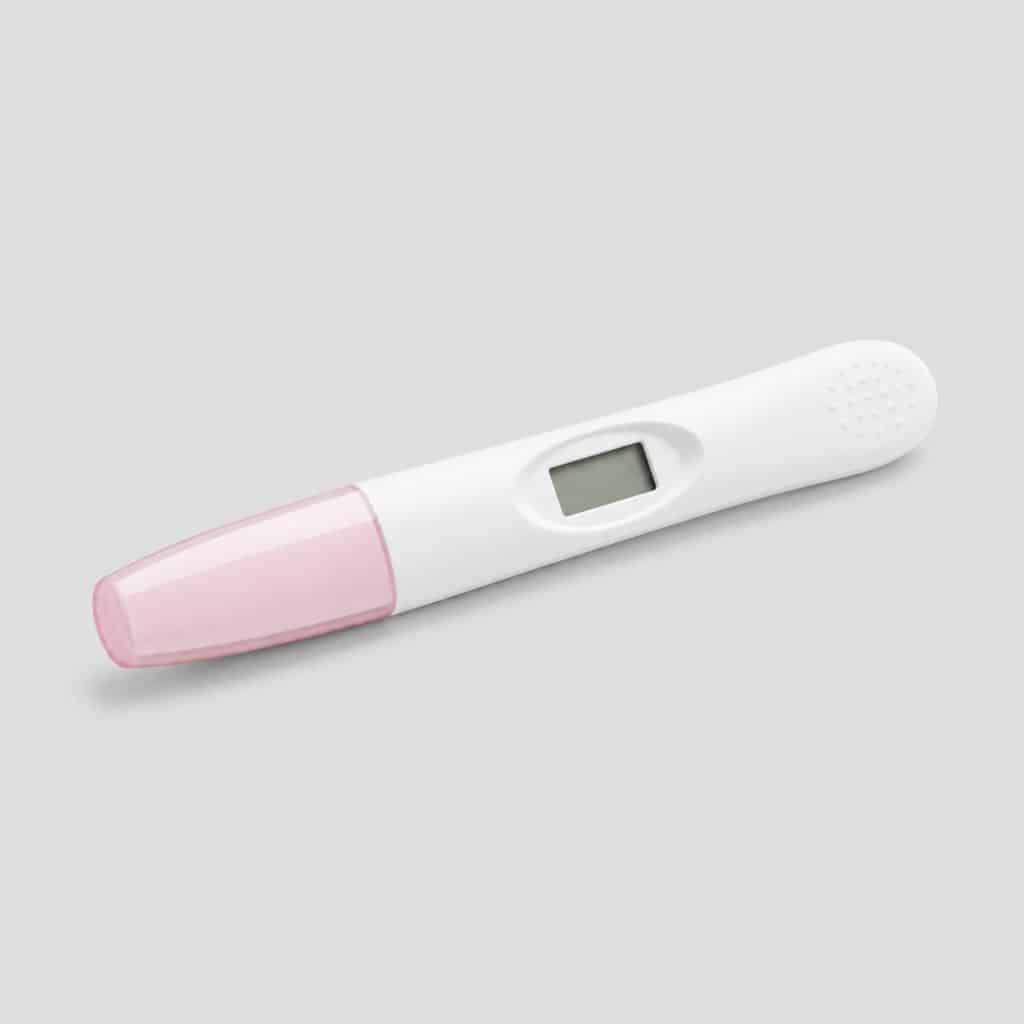 Boîtier de test de grossesse numérique posé sur fond clair