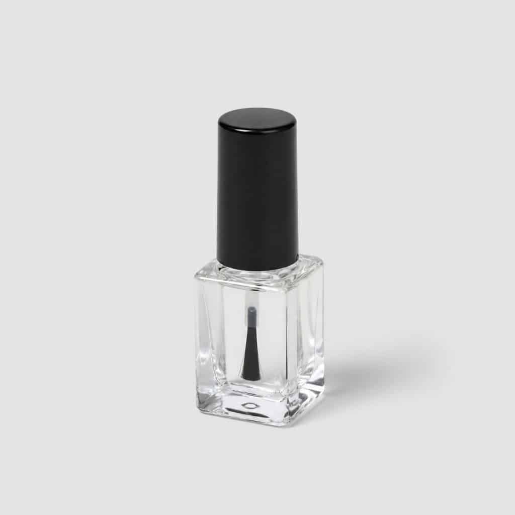 Petit flacon de vernis transparent avec pinceau applicateur posé seul sur fond neutre clair
